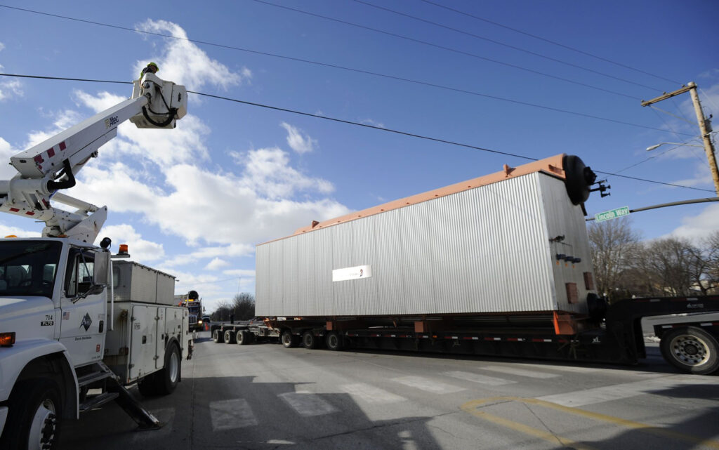 A City Of Ames Electric Department Employee Holds A Power Line To Allow