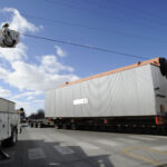 A City Of Ames Electric Department Employee Holds A Power Line To Allow